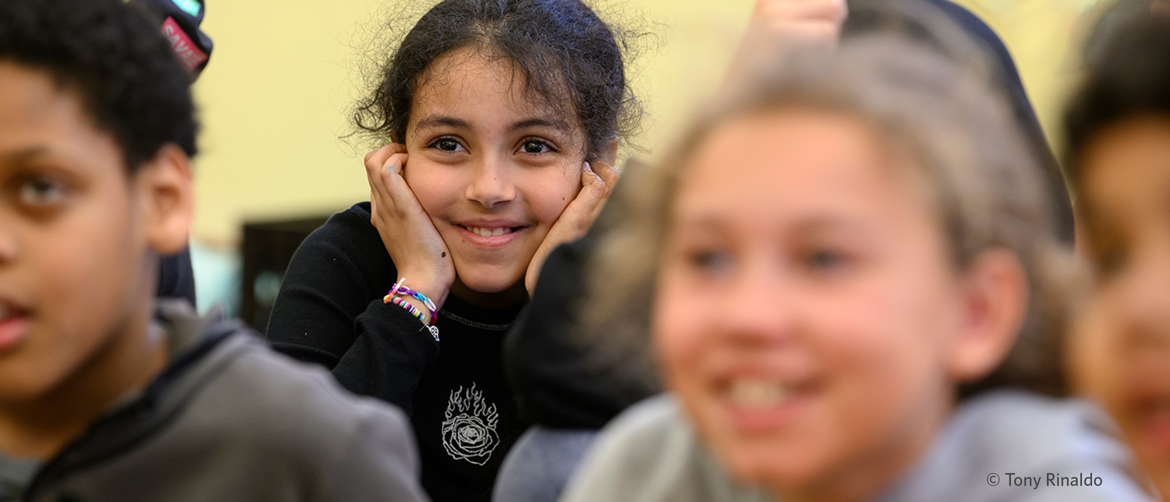 3 smiling students in museum classroom.