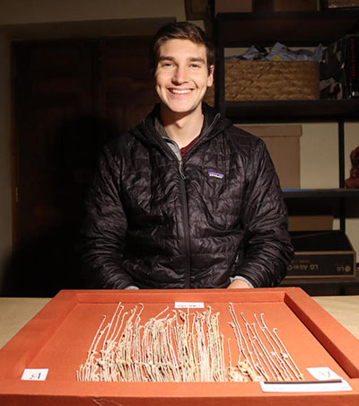 mack fitzpatrick smiling with khipus on desk.