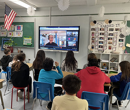 students in classroom watch virtual maya program on screen.
