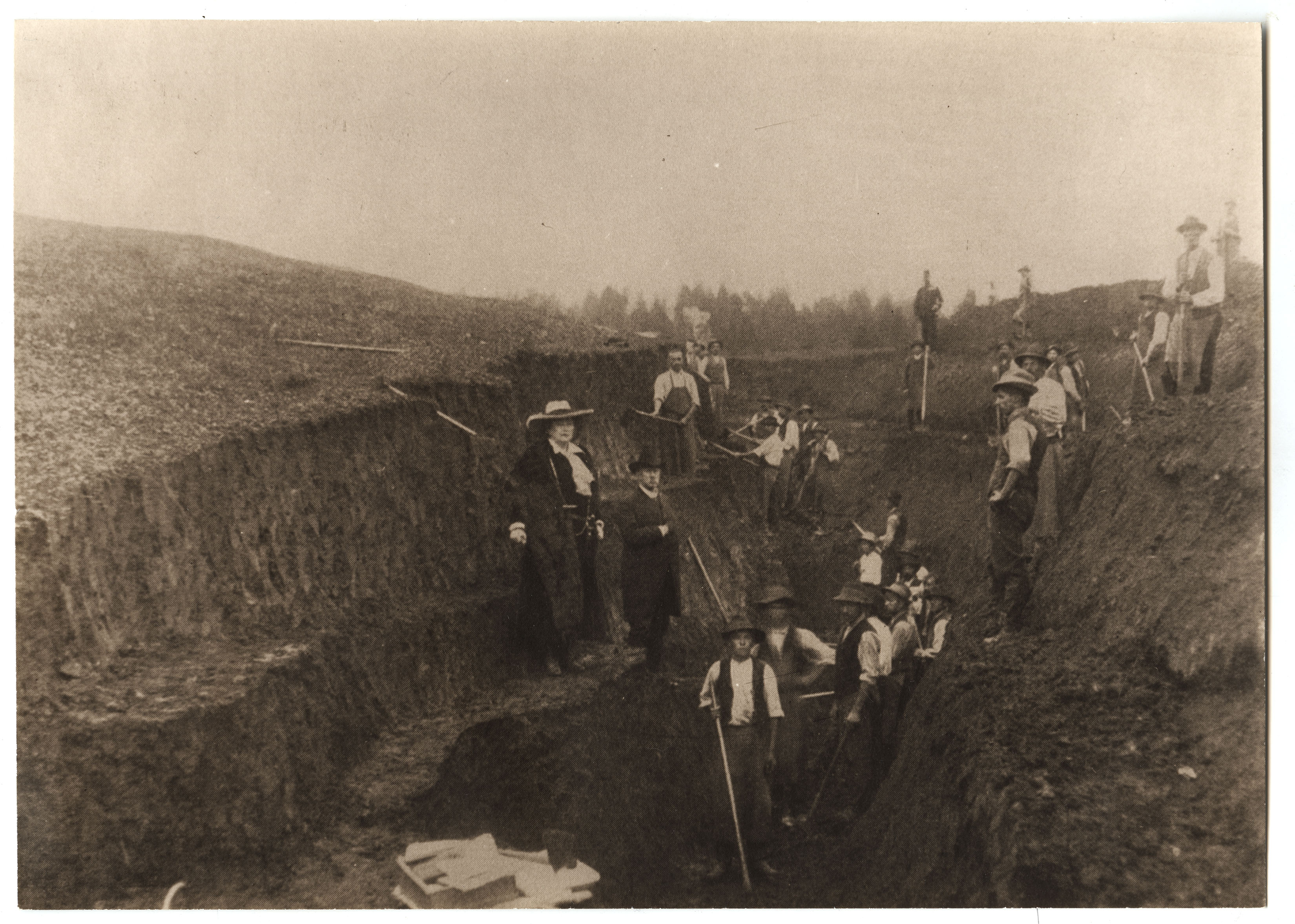 workers in archaeologic dig trench with digging implements