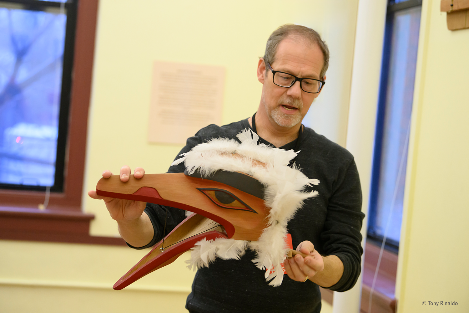 museum educator demonstrates raven mask.