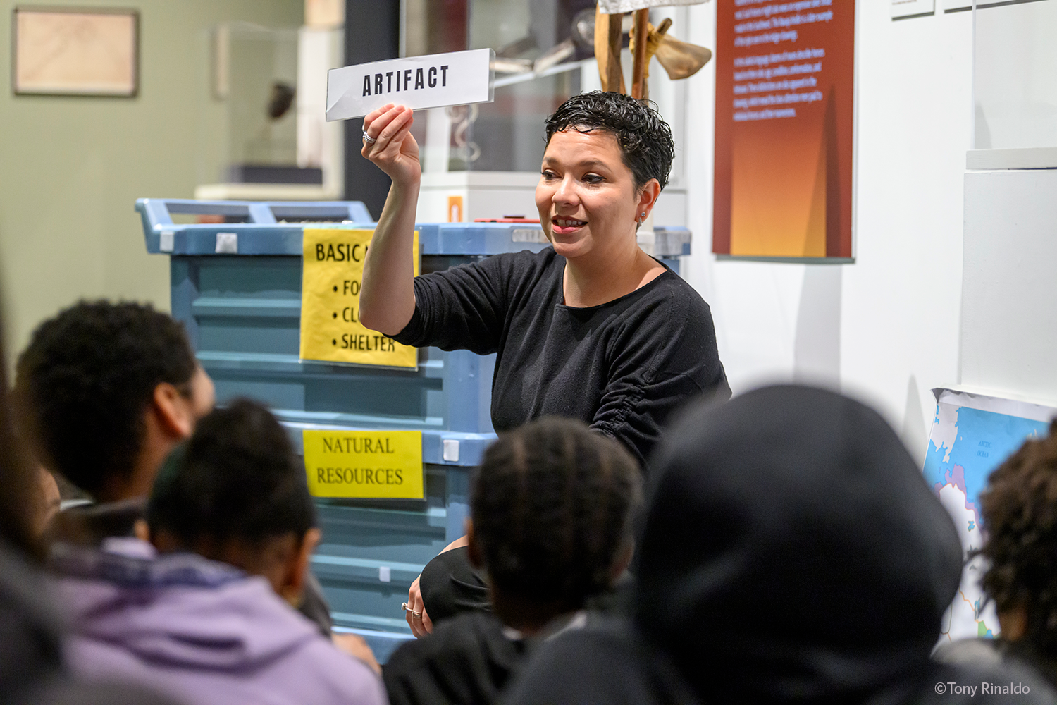educator holds up artifact sign in gallery with elementary school students.