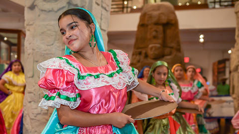 folk dancer with basket in gallery.