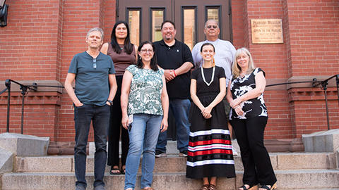 group of staff members and tribal visitors standing on the museum's front steps