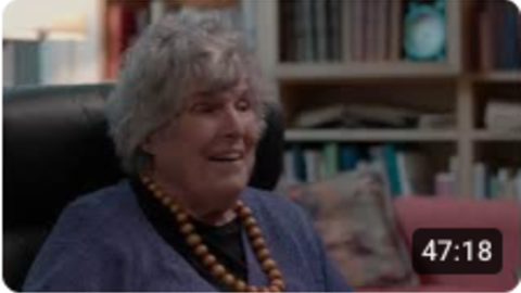 smiling coggins in her home with books in the background.