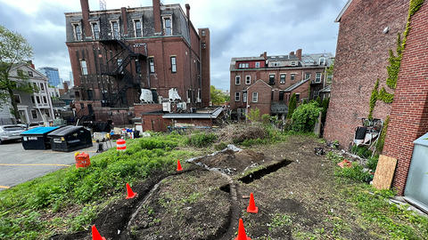 archaeological excavation in boston surrounded by buildings.