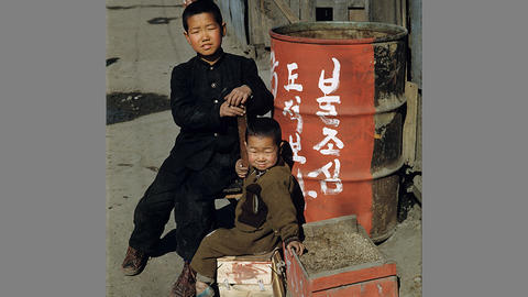 2 children next to a barrel with korean writing on it.
