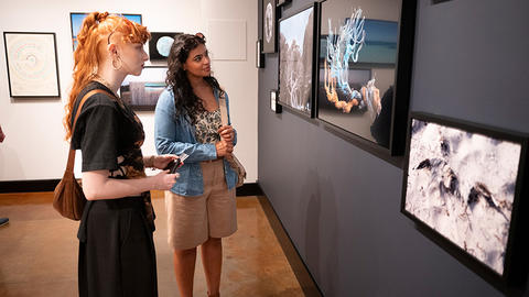 2 visitors look at photo exhibit.