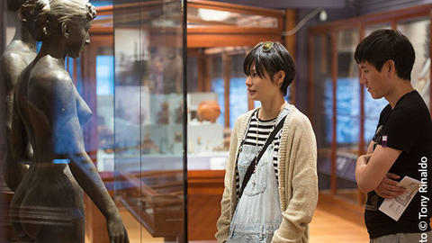 two visitors look at two human sculptures.