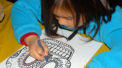 girl draws mexican skull mask.