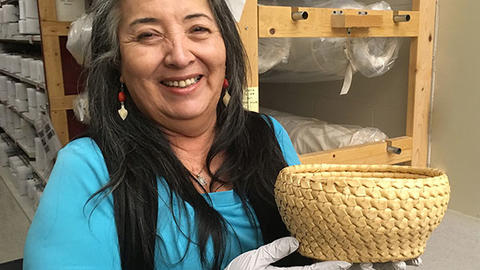 smiling woman holds basket in collections area.