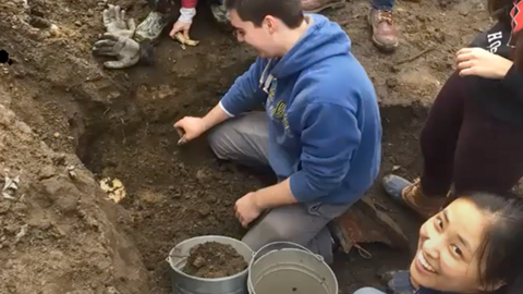 harvard students smile as they excavate harvard yard.