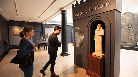 2 visitors approach exhibit statue.