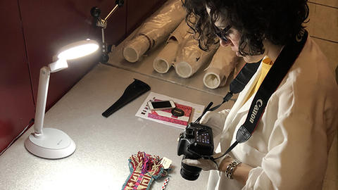 Woman holding camera while looking at a textile