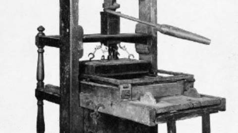 Black and white image of an early printing press.