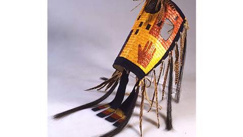 Yellow and red horse mask of woven fibers, feather hangings, and horse hair.