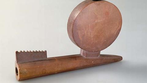 Wooden pipe with circular attachment.