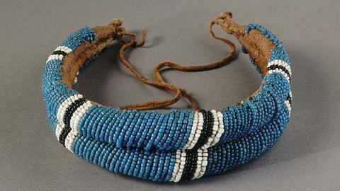 A beaded blue bracelet with a vertical stripe pattern of black surrounded by white.