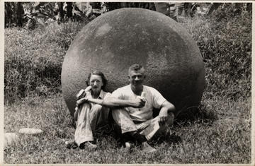 Eleanor Lothrop and Samuel Kirkland Lothrop sitting against stone sphere eating bananas