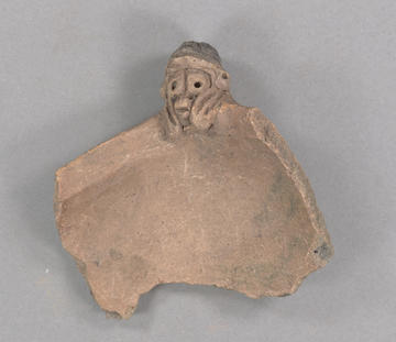 Reddish brown ceramic sherd with a sculpted face on it