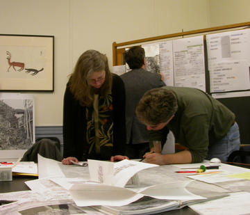 People bending over drawings on table