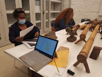 two women work at table with laptop and headrests.