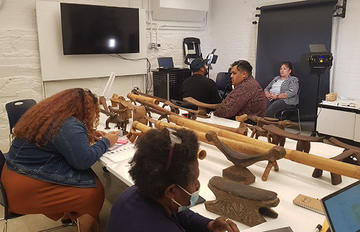 group of oceanic peoples working with headrests in museum.