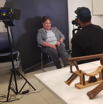 woman poses in front of screen with headrests on table.