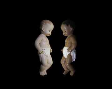 two baby dolls face each other, one white and one black.