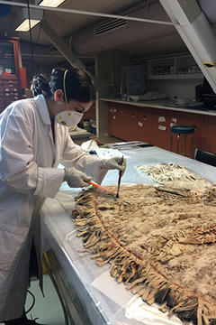 Woman in lab coat cleaning a hide jacket