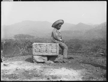 Photograph of a child seated on Altar S at the Mesoamerican archaeological site of Copán, 2004.24.242