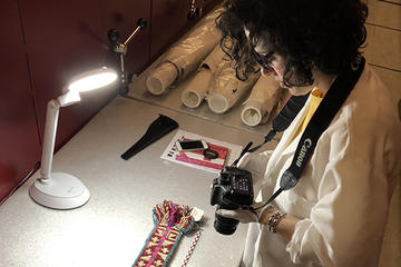 Woman holding camera while looking at a textile