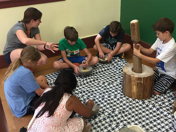 educator and students grind maize by hand.