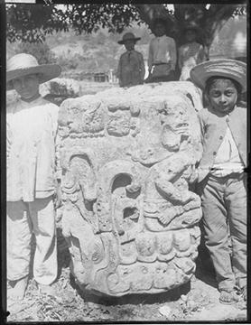 historic photo of two boys near ancient maya sculpture.
