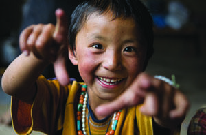 smiling child in nepal gestures to camera.