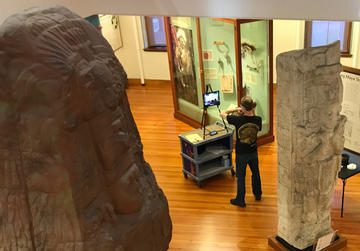 museum educator at cart in gallery runs live virtual class.