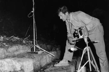 black and white photo of Ian Graham on steps with camera at night