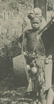 detail of the group photo of filipinos with instruments. the detail is a young filipino with a single gong worn over the shoulde