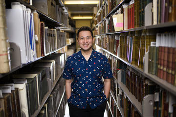 Portrait of Ricky Punzalan smiling amid archive shelves.