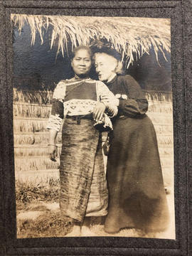 filipina with slight smile and one of the white sisters drawing her head close to filipina's.