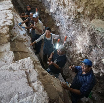 group in a trench reburying a stucco façade