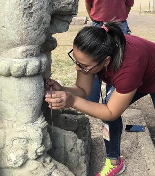 Woman leaning in towards a stone sculpture to take a sample