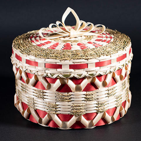 Small red and white hand woven basket against a black background