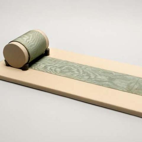 Blue silk sash partially rolled onto storage cylinder