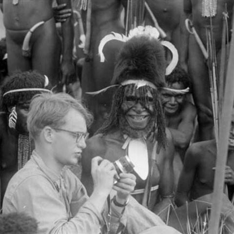Michael Rockefeller posing with grinning warrior