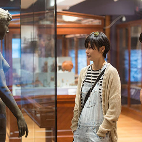 two visitors look at two human sculptures.
