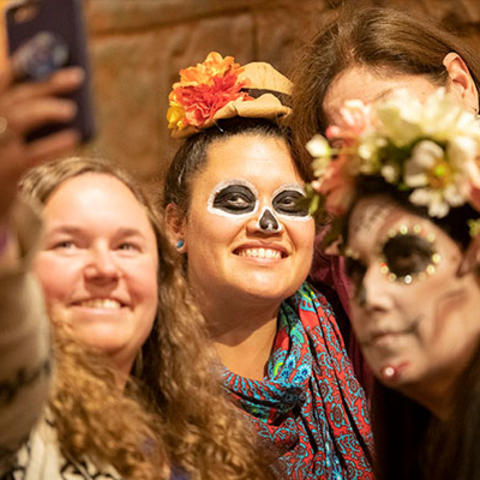 smiling costumed people take selfie.