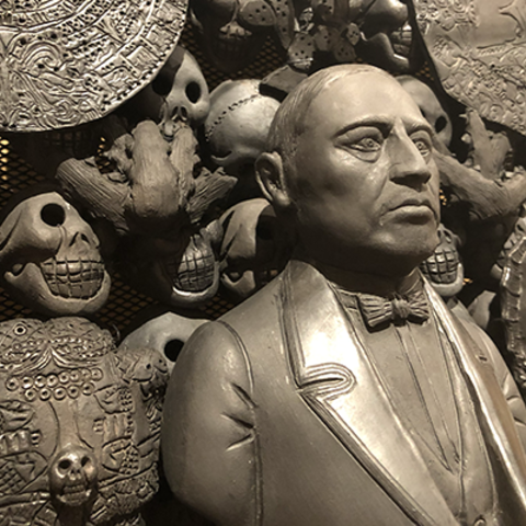 detail of clay sculpture portrait of man surrounded by skulls.