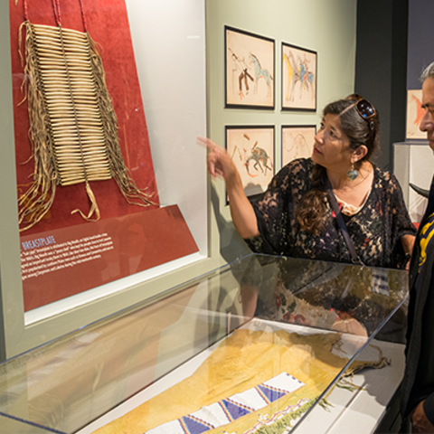 native american man and woman looks at breastplate.