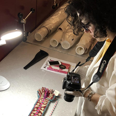 Woman holding camera while looking at a textile